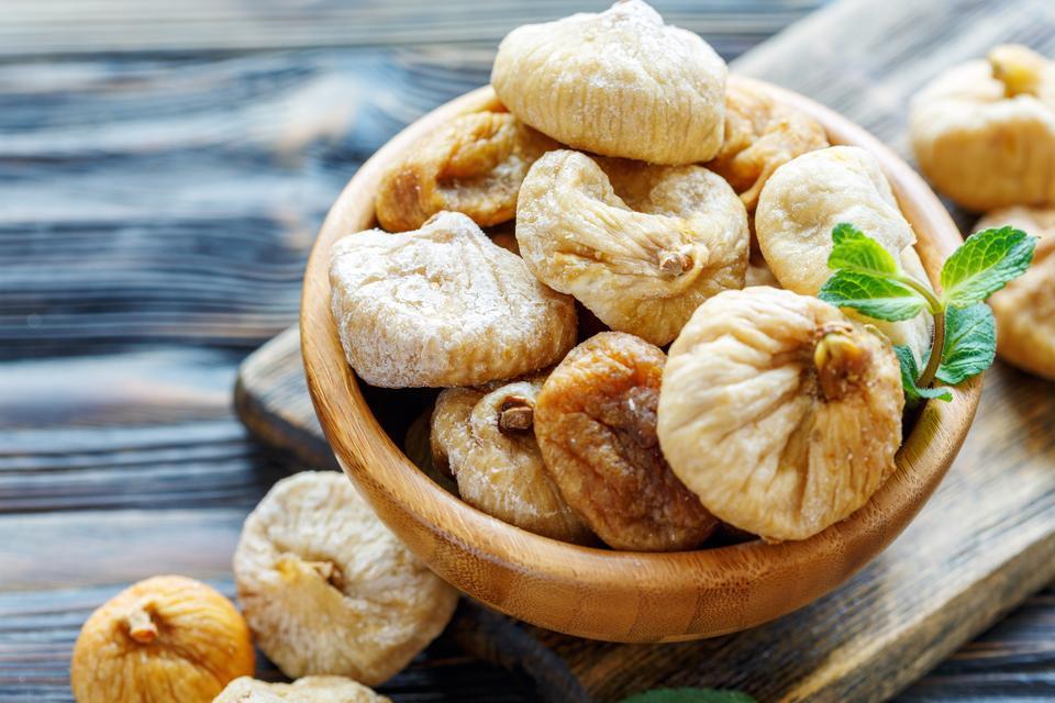 Delicious dried figs in a wooden bowl closeup, selective focus.